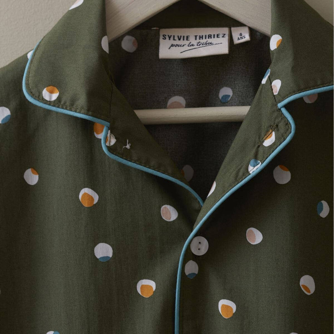 Sylvie Thiriez Kids Confetti Pajamas shirt, close-up view of olive green cotton collar, blue piping, white buttons, and…
