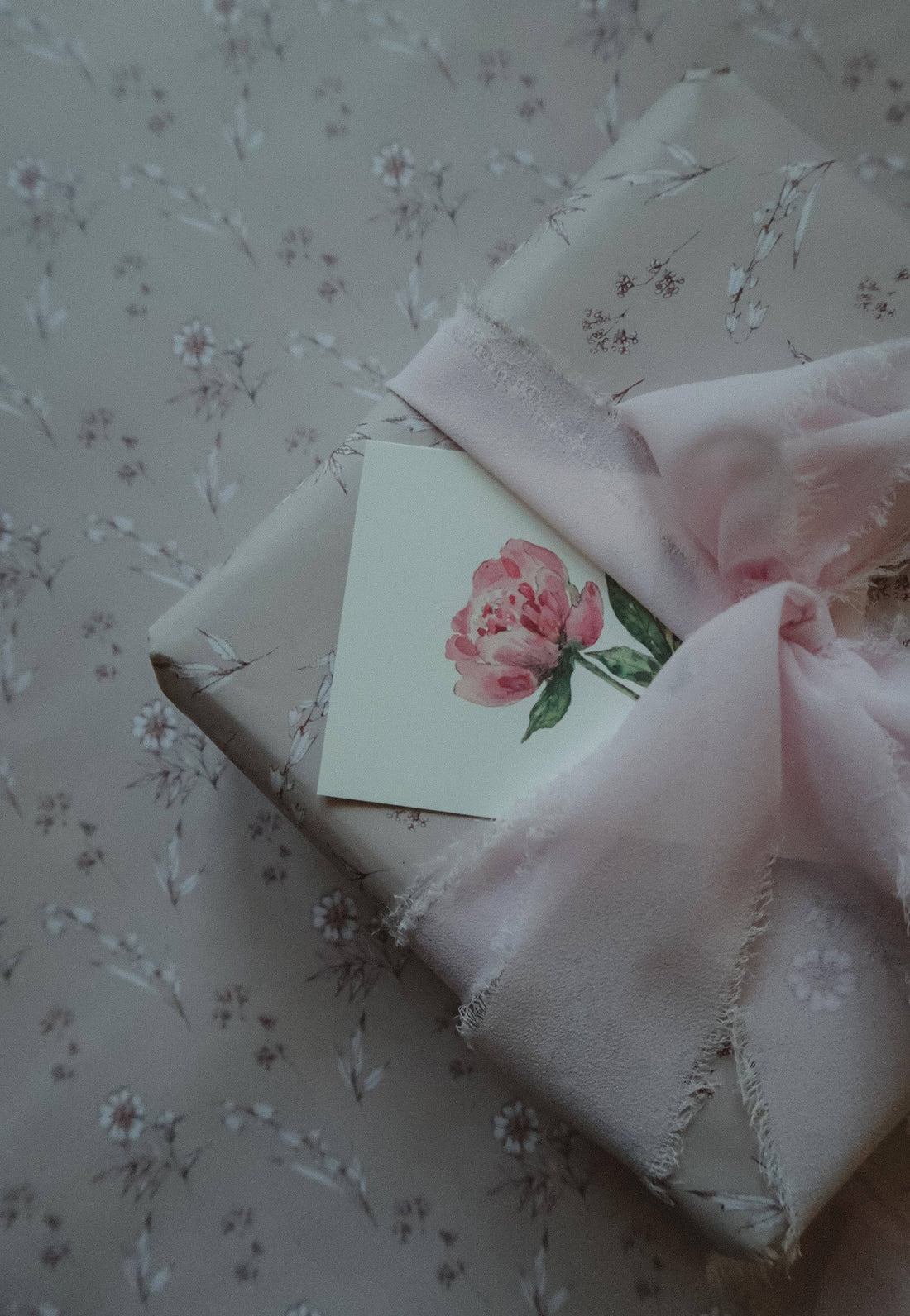 Vintage Blooms wrapping paper, light pink floral pattern on wrapped gift, with crinkled pink ribbon and watercolor peony…