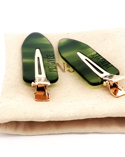 
                    
                      Peignee Paris Emerald hair clips, mottled emerald green cellulose acetate, gold-toned clasps, close-up on textured beige…
                    
                  