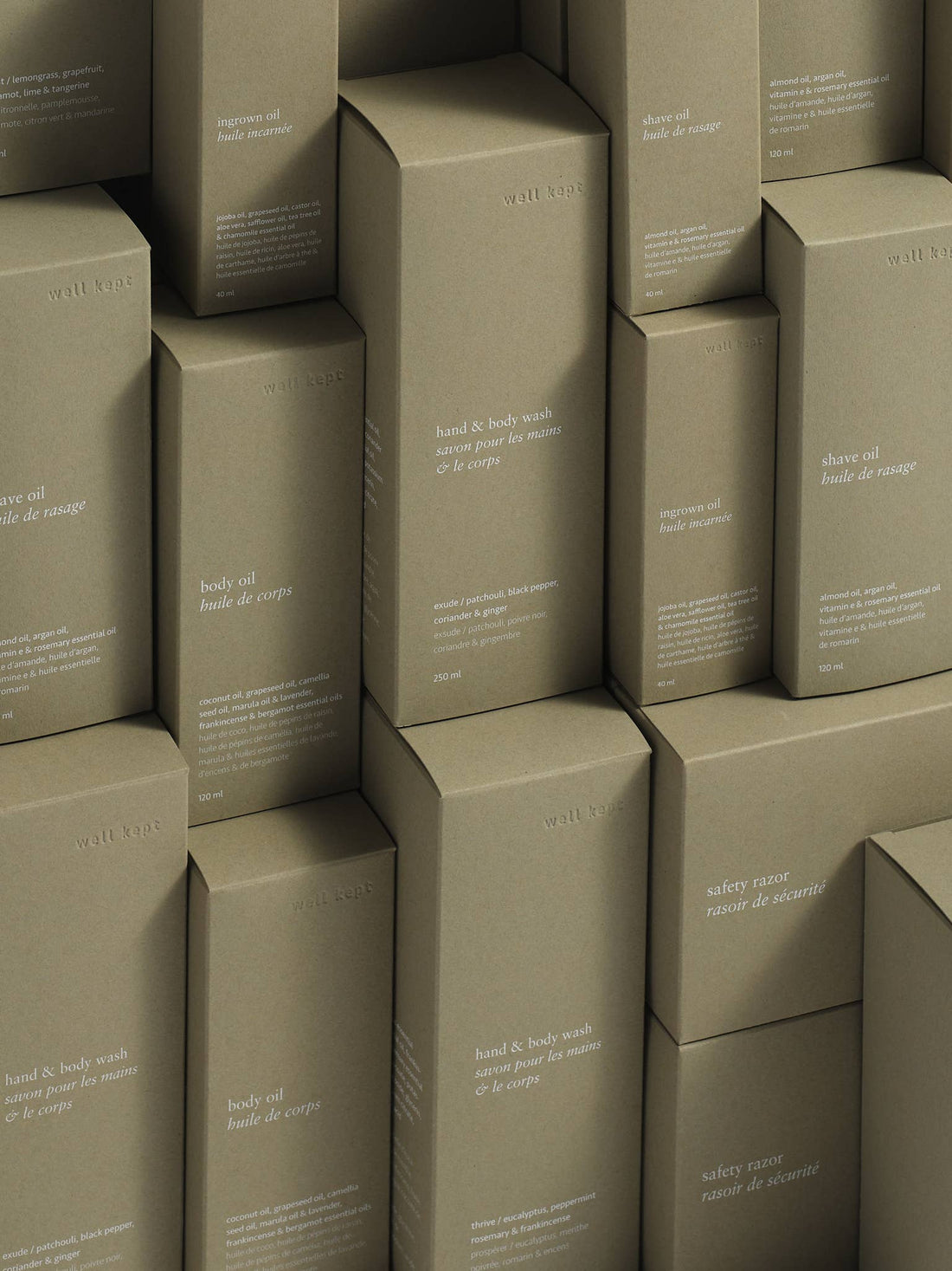 Well Kept Shave Oil boxes and other wellness products, stacked natural brown cardboard, white text detail view.
