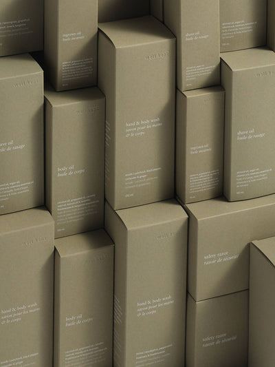 
                    
                      Well Kept Shave Oil boxes and other wellness products, stacked natural brown cardboard, white text detail view.
                    
                  