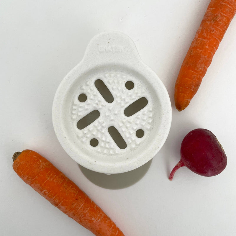 Fort & Field Japanese Ceramic Vegetable Grater Set, white porcelain, top-down flat lay with carrots and radish for scale.