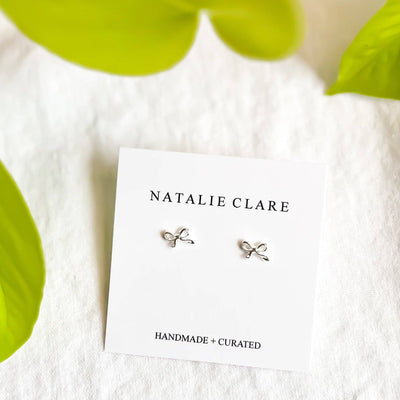 
                    
                      Mini Silver Bow stud earrings, 925 sterling silver, pair displayed on white product card, flat lay.
                    
                  