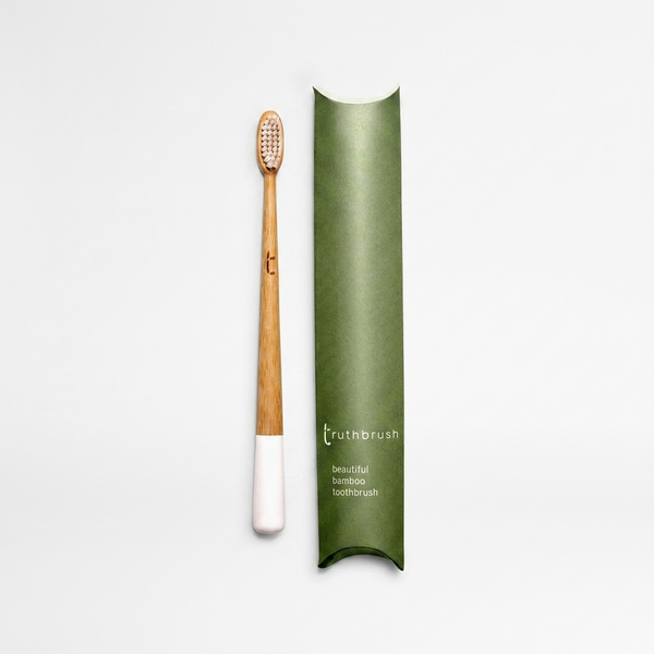 Truthbrush Cloud White manual toothbrush, natural bamboo handle with white painted tip and light bristles, flat lay with…