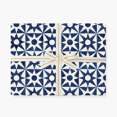 
                    
                      Celebrating Stars wrapping paper, blue and white abstract star pattern, wrapped as a gift with cream and gold ribbon, front…
                    
                  
