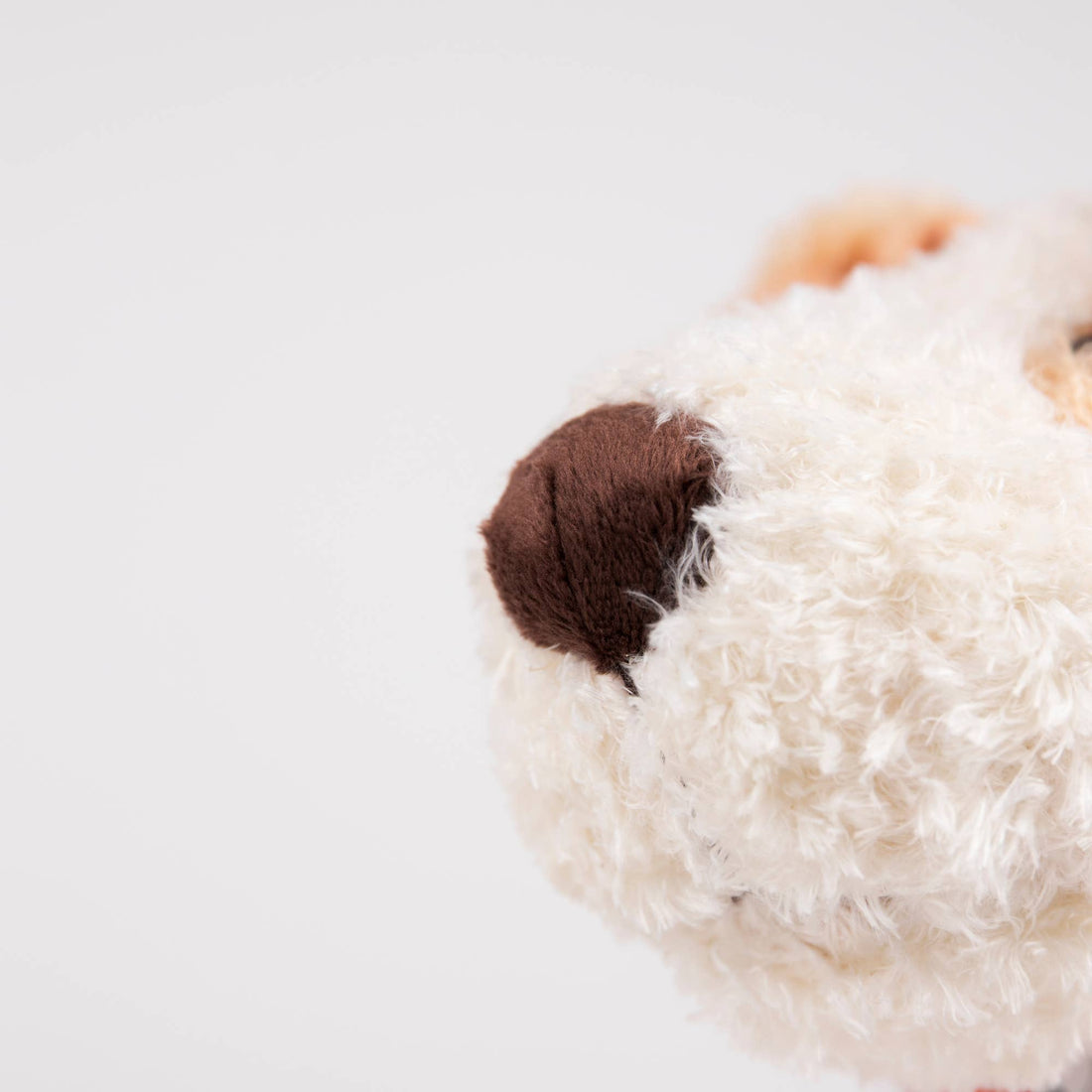 Eliot plush stuffed dog, close-up view of fluffy cream polyester fur around the brown nose.