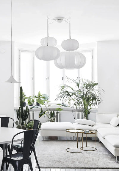 
                    
                      Green Home Book inspired interior: airy living room, many green plants by window, minimalist white sofa, natural light.
                    
                  