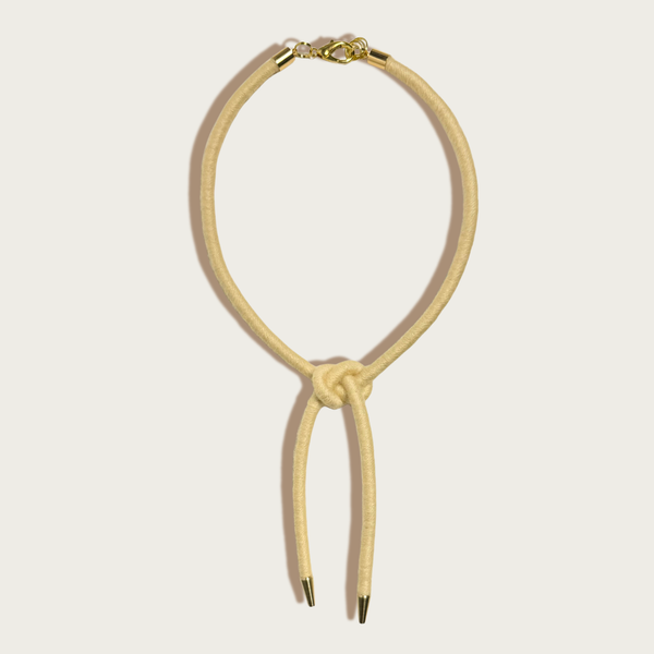 Sasha Shoelace Square Knot bolo tie, buttercream wool-wrapped cording, raw brass tips, gold-plated lobster clasp, front flat…