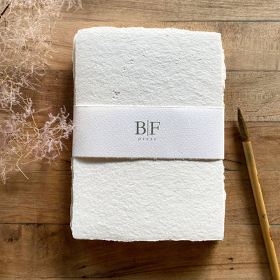 
                    
                      Bat Flower Press Ivory Handmade Paper Set, textured recycled cotton sheets, torn edges, branded belly band, flat lay.
                    
                  