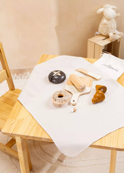 
                    
                      Wooden Bakery Set toys with dark brown bread, light wood bagel, croissant, and white knife, tabletop display.
                    
                  