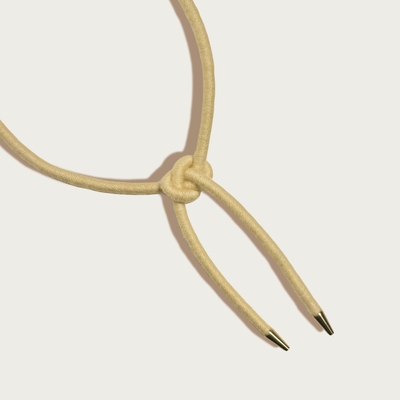 
                    
                      Shoelace Square Knot Bolo tie, buttercream wool-wrapped nylon cord and raw brass tips, close-up view of square knot and…
                    
                  