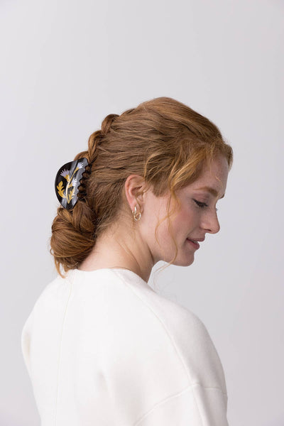 
                    
                      Milk Thistle hair claw, black acetate with yellow and purple thistles, worn in a model's braided bun.
                    
                  