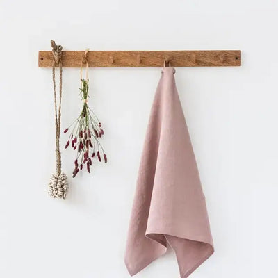 
                    
                      Premium Linen Tea Towel in blush pink, 100% linen, hanging folded on a wooden peg rail.
                    
                  