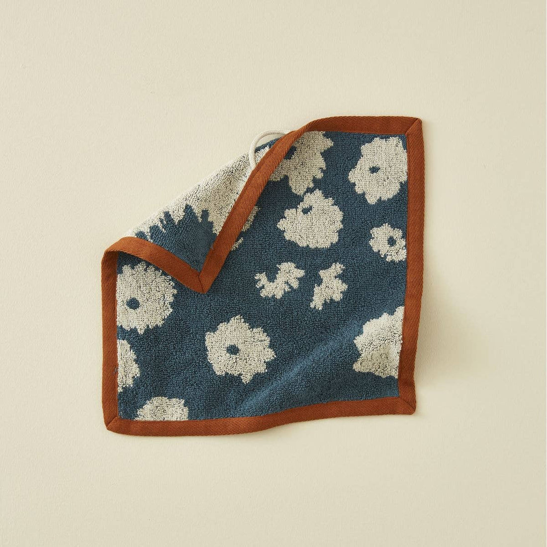 Sylvie Thiriez Coup de Foudre washcloth, blue cotton with cream floral pattern and terracotta border, folded with hanging…