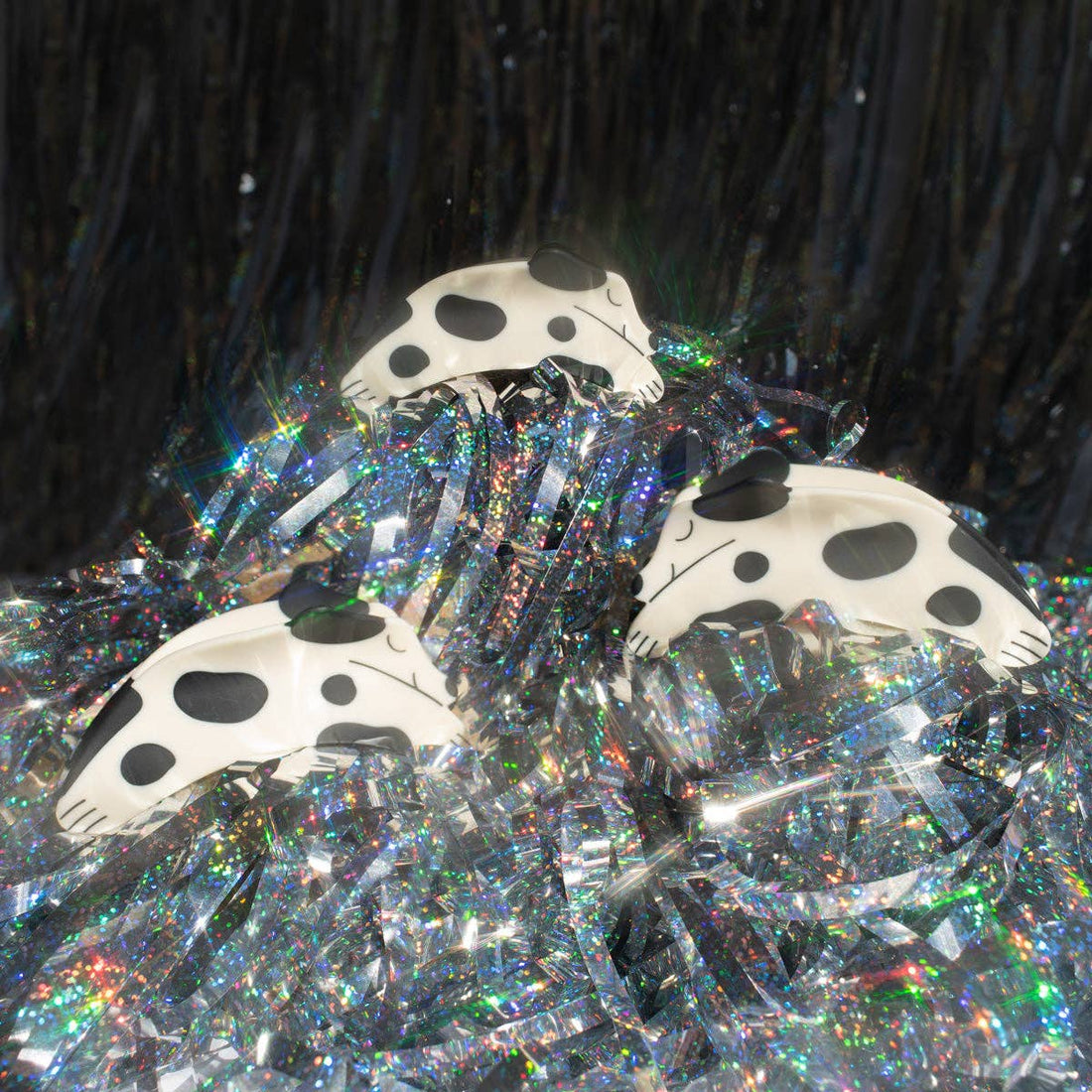 Puppy Claw Spotted Dog hair clips, white cellulose acetate with black spots, trio displayed on shimmering holographic tinsel.