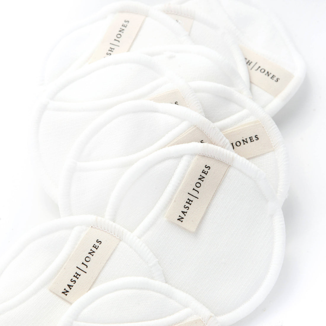 Nash and Jones Bamboo and Cotton Reusable Facial Pads, white, stacked close-up showing soft fabric texture and brand labels.