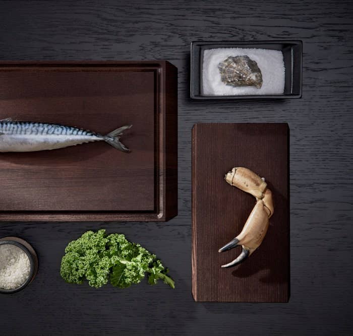 Rå ash wood chopping board with mackerel, and a smaller Rå serving tray with crab claw, overhead view.