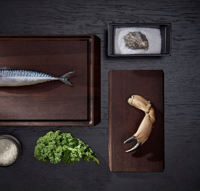 
                    
                      Rå ash wood chopping board with mackerel, and a smaller Rå serving tray with crab claw, overhead view.
                    
                  