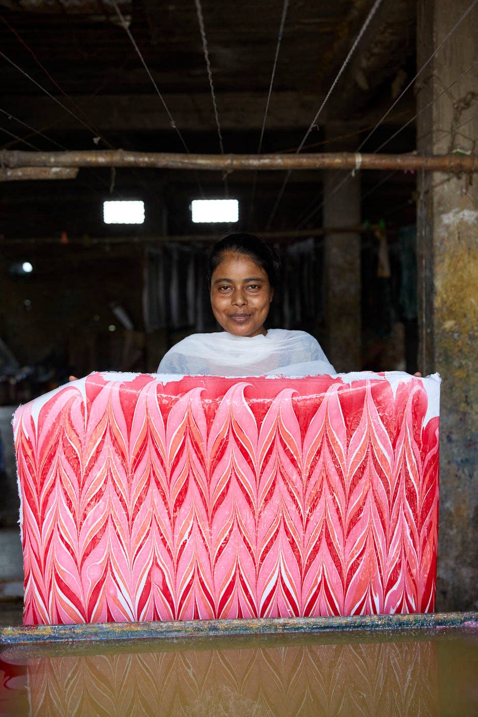 Candy Stripes Sugar Spice hand marbled wrapping paper, held by an artisan showing the red, pink, white feather pattern and…