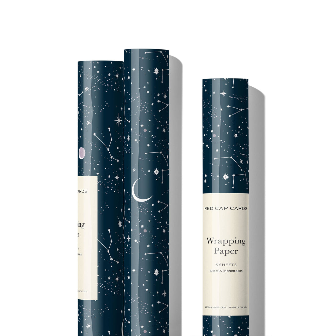 Red Cap Cards Moon and Stars wrapping paper, dark blue with white moon and star pattern, three rolls standing upright,…
