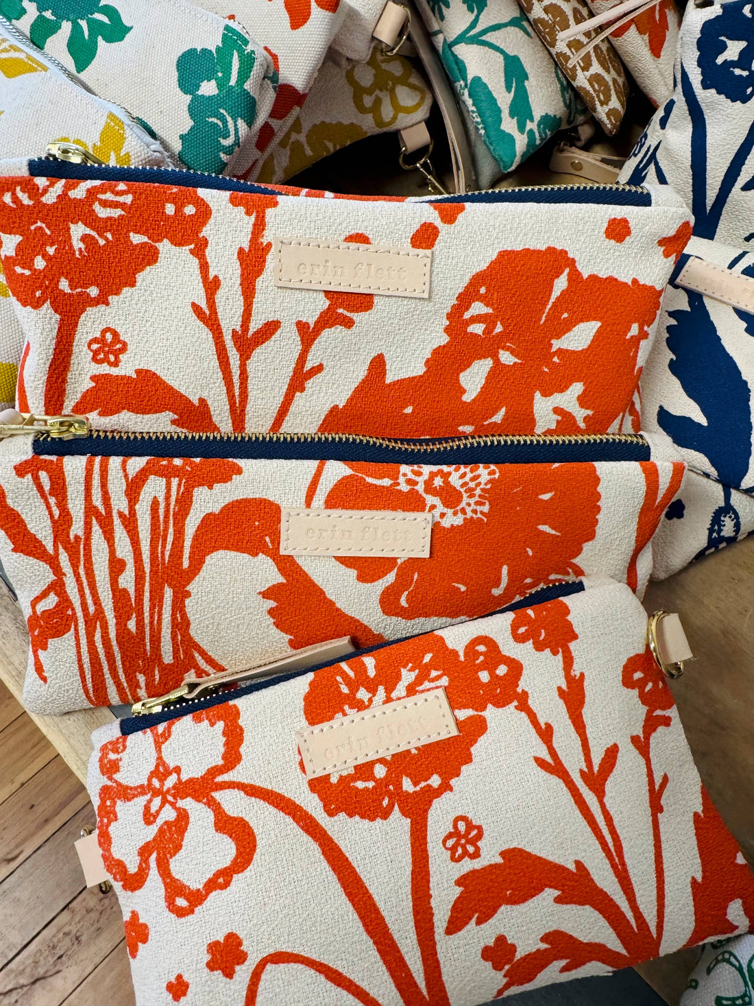 Erin Flett Laura Pouch, Flaggy Meadow orange floral cotton barkcloth, close-up of brass zipper and leather tag on stacked…