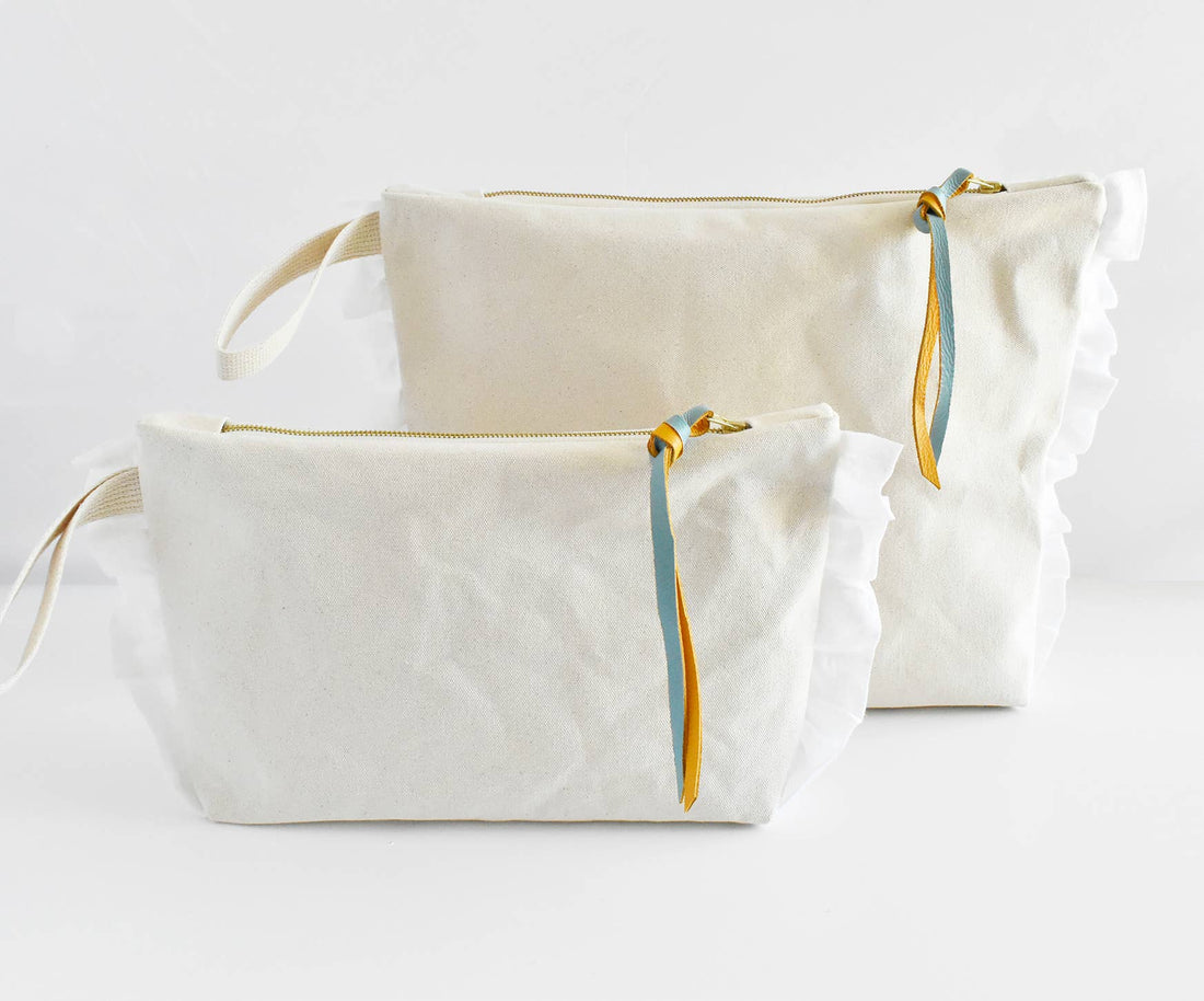 Natural cotton Ruffle Zipper Pouches, two sizes, with white ruffles, gold zippers, and blue/yellow leather pulls visible.