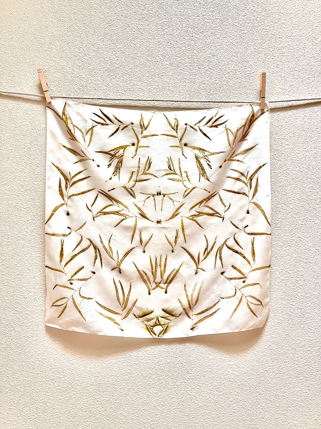Eucalyptus Grove Silk Bandana Scarf, natural eco-printed eucalyptus leaf pattern on light silk, hanging on clothesline with…