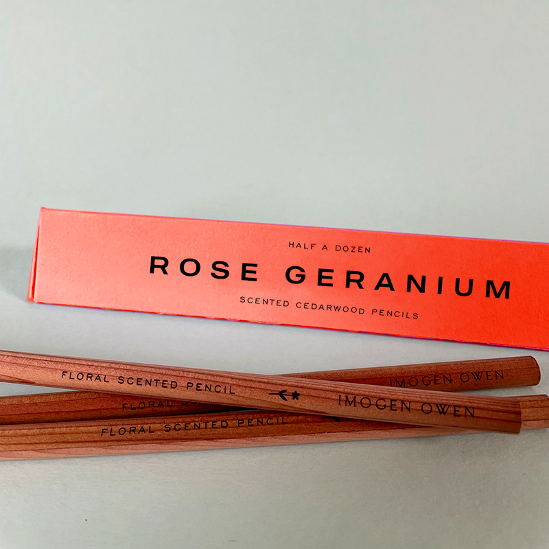 Imogen Owen Rose Geranium Scented Pencils, natural cedarwood pencils with coral box, flat lay close-up.