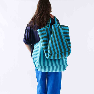 
                    
                      Elisabeth cotton tote bag in turquoise and olive stripes, carried over shoulder by person, back view, with a second matching…
                    
                  