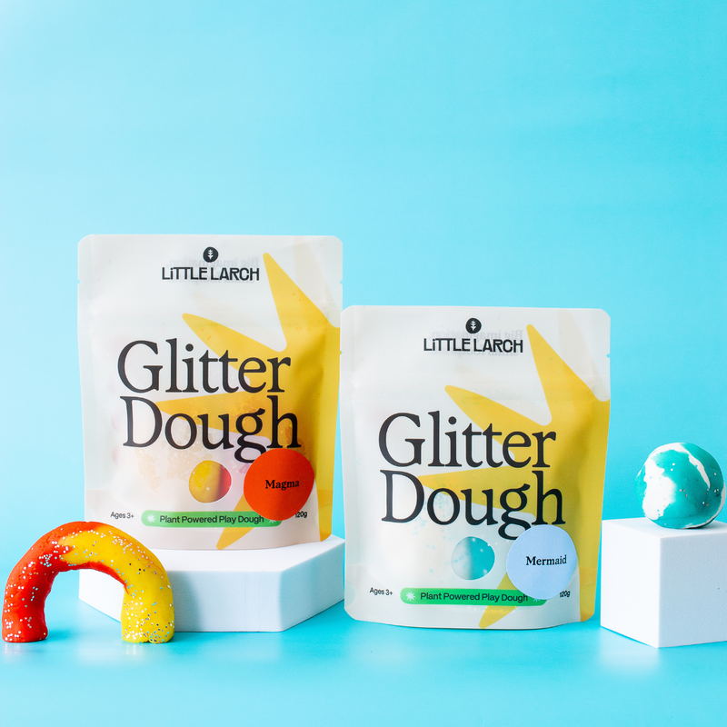 Two packages of Little Larch Glitter Dough on a blue background with colorful play dough items.