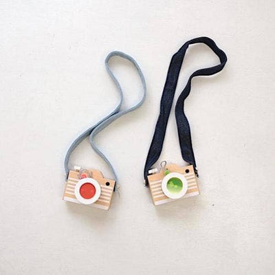 
                    
                      Two Kaleidoscope Play Cameras: beechwood toys with red and green acrylic lenses, light blue and dark blue straps, flat lay.
                    
                  