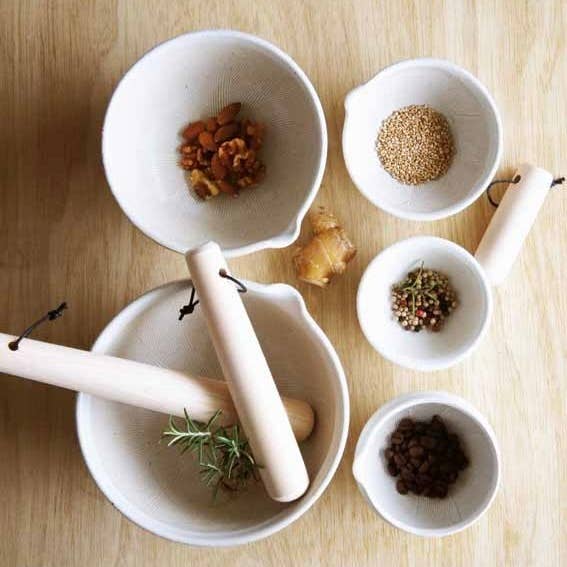 Japanese Hinoki Cypress Wood Surikogi pestles, light natural wood, flat lay in mortar bowl with fresh rosemary.