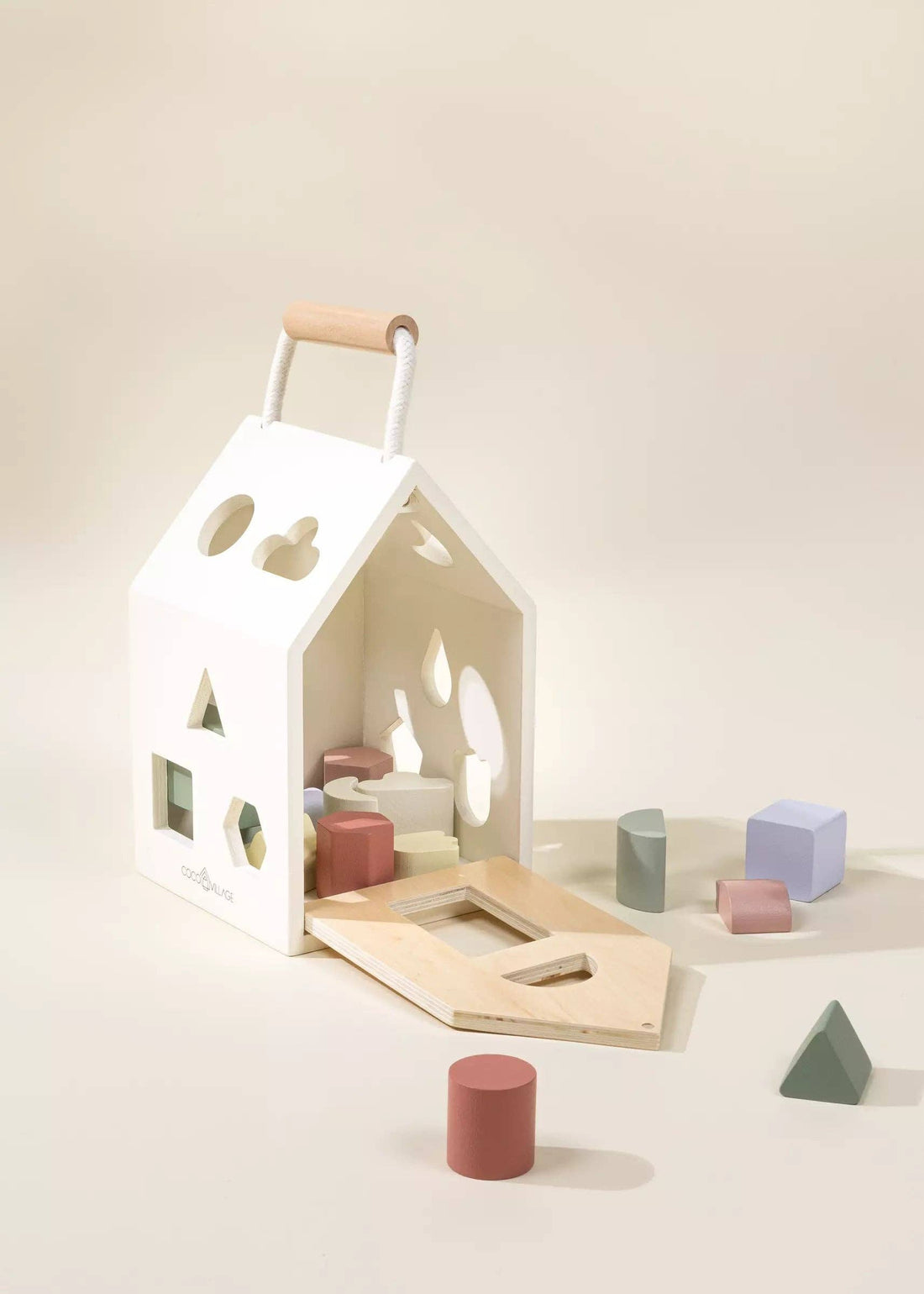 Coco Village Wooden Shapes Sorting House, white, natural wood handle, open plywood base, pastel sorting blocks scattered.