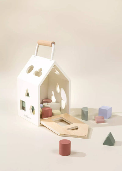 
                    
                      Coco Village Wooden Shapes Sorting House, white, natural wood handle, open plywood base, pastel sorting blocks scattered.
                    
                  