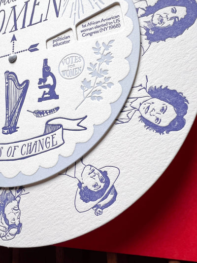 
                    
                      Brilliant Women Spinner, cotton paper close-up: blue letterpress illustrations like harp, microscope, and 'VOTES FOR WOMEN'…
                    
                  