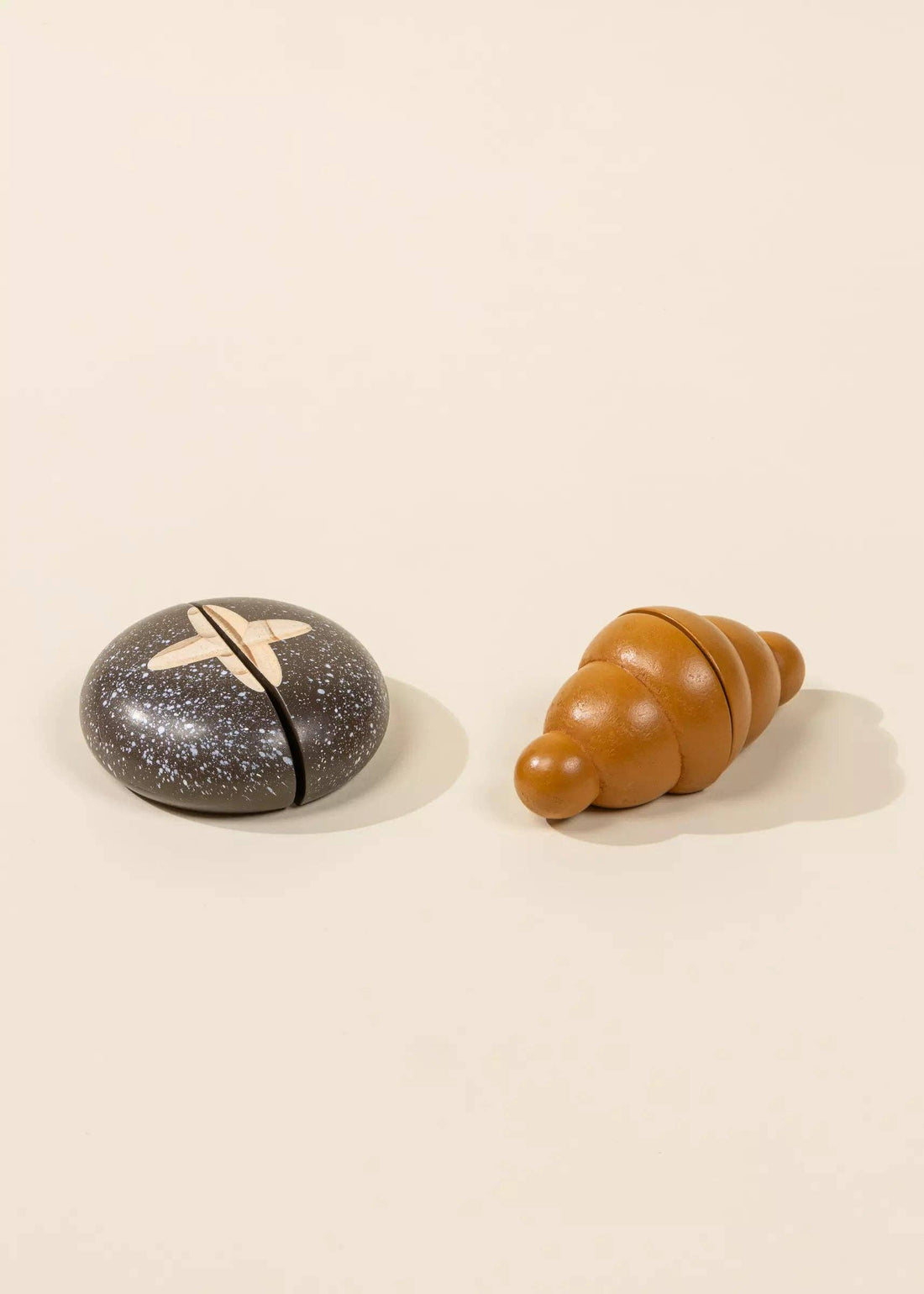 Wooden Bakery Set toys: dark speckle bread loaf and light brown croissant, side-by-side on white background.