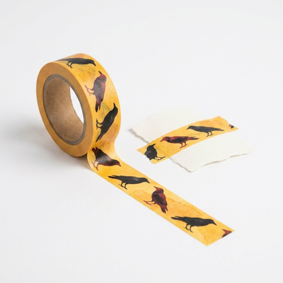 
                    
                      Blackbird Letterpress Flying Crows washi tape, yellow with black and red crow pattern, roll unfurling with tape adhered to…
                    
                  
