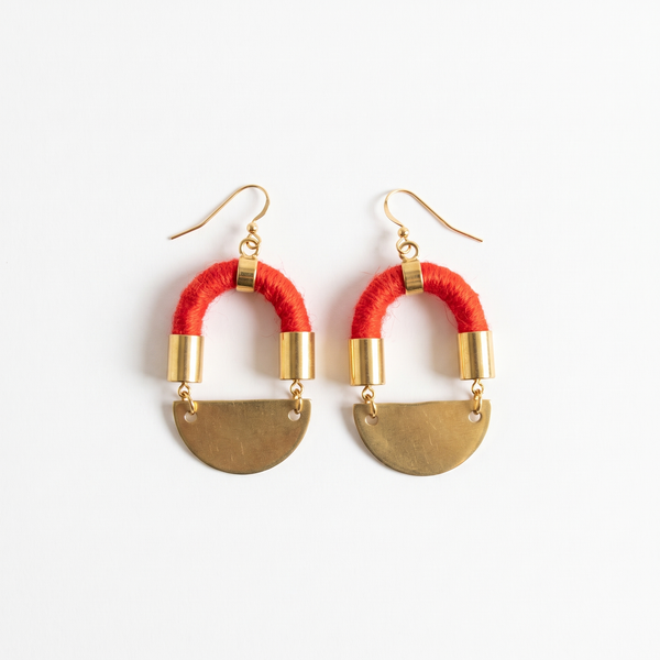 Sasha Half Moon earrings, red yarn-wrapped cording with brass moon pendants and gold-plated hardware, flat lay pair on white.