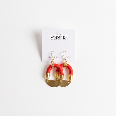 
                    
                      Sasha Half Moon earrings, red yarn-wrapped cording with brass moon pendants and gold-plated hardware, flat lay on product…
                    
                  