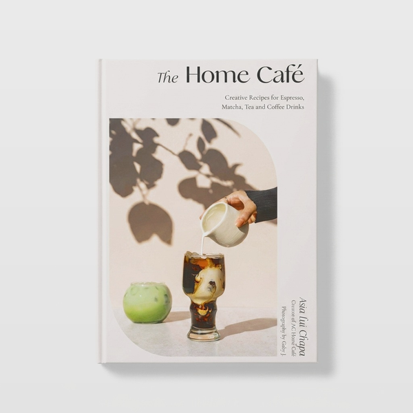 Macmillan Publishers Home Café Recipes cookbook, light cream cover showing hand pouring cream into iced coffee, front view…