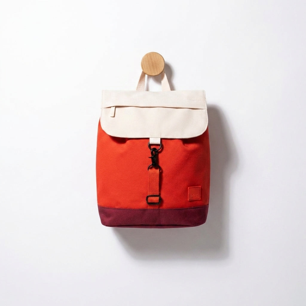 Lefrik Kaut Mini Backpack Cherry Block studio product photo hanging from a wooden wall hook on a neutral off-white background