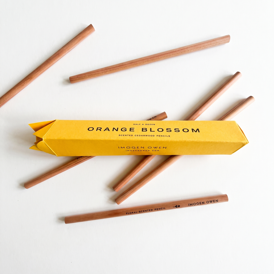 Imogen Owen Orange Blossom Scented Pencils, yellow box and natural cedarwood writing pencils, flat lay group.