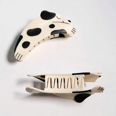 
                    
                      Winona Irene Puppy Claw Spotted Dog hair clip pair, black and white spotted cellulose acetate, one closed top view, one open…
                    
                  