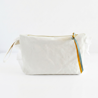 
                    
                      Celina Mancurti Ruffle Cotton Zipper Pouch studio product photo hanging from a wooden wall hook on a neutral off-white…
                    
                  