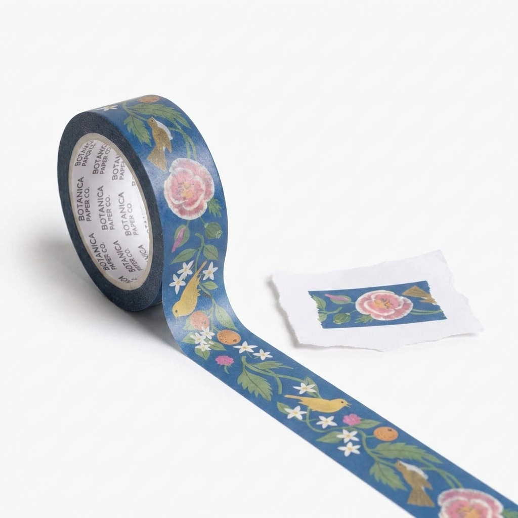 Botanica Paper Co. Song Birds washi tape, blue with yellow birds, pink flowers, and green leaves, partially unrolled with a…