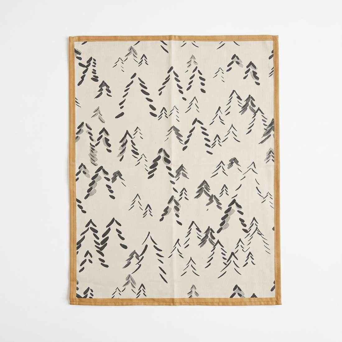 Spitzberg cotton tea towel, off-white with dark gray abstract trees, tan stitched border, flat lay.