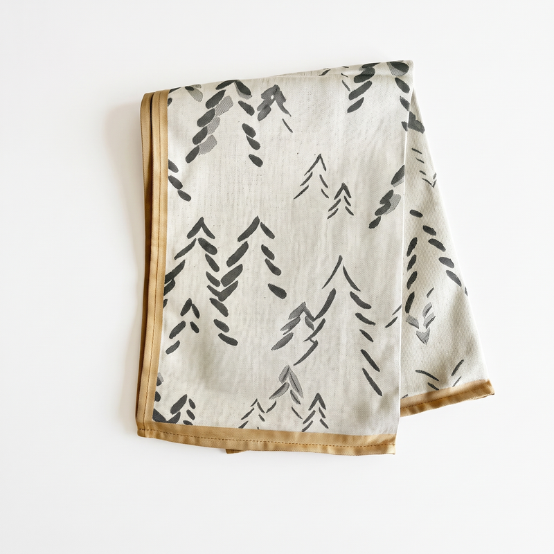 Sylvie Thiriez Spitzberg Cotton Tea Towel, natural with dark gray abstract tree pattern, tan border, folded flat lay on…
