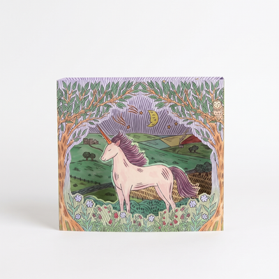 
                    
                      Art Angels Twilight Unicorn die-cut card, illustrated by Fee Greening, green landscape, purple trees, front on white.
                    
                  