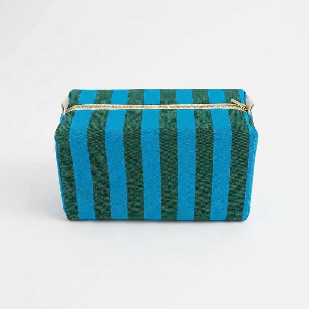 Rose in April Vic Toiletry Bag - Stripes Turquoise / Olive studio product photo hanging from a wooden wall hook on a neutral…
