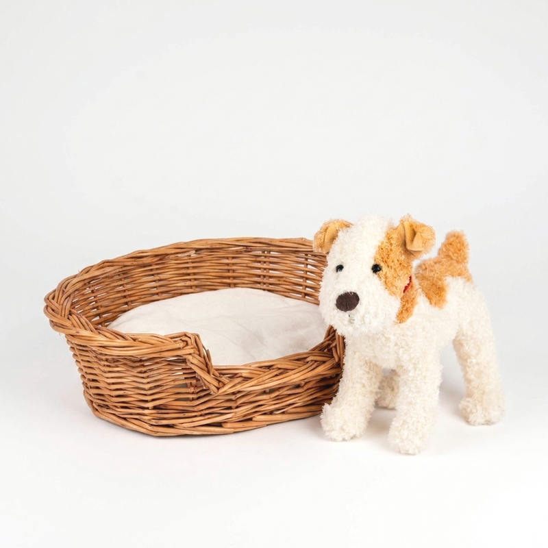 Egmont Wicker Dog Basket with Cushion, natural woven willow and light cotton, front view with a toy dog for scale.
